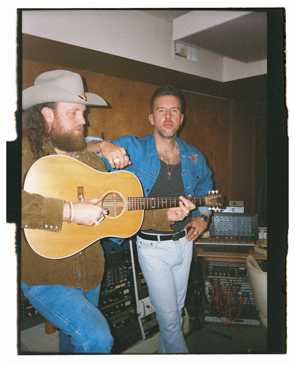 Brothers Osborne performaers. One is playing the guitar and the other is posing for the camera while leaning on his brother's shoulder.